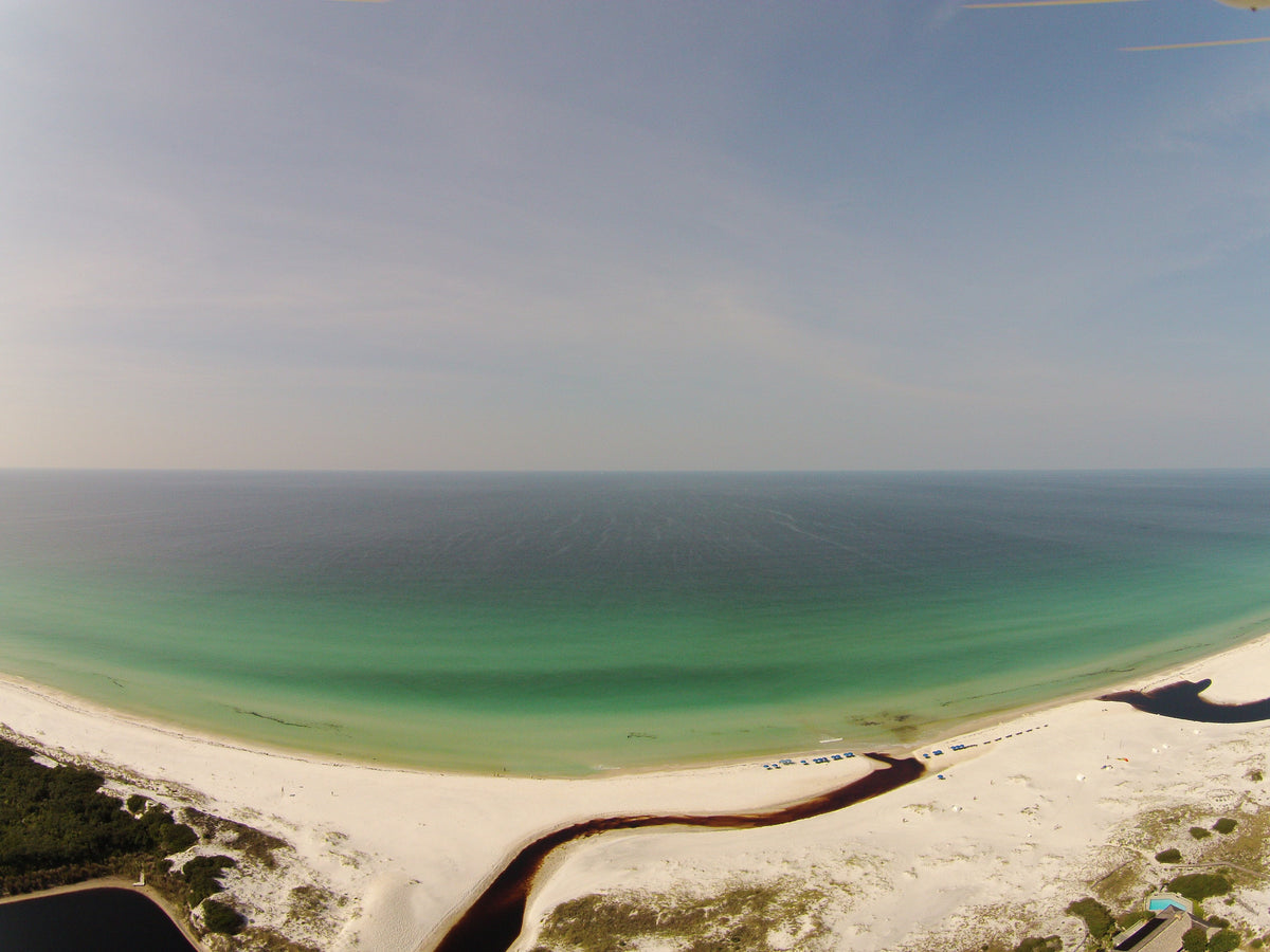 Aerial view of a coastal dune lake outfall meeting the Gulf of Mexico along 30A